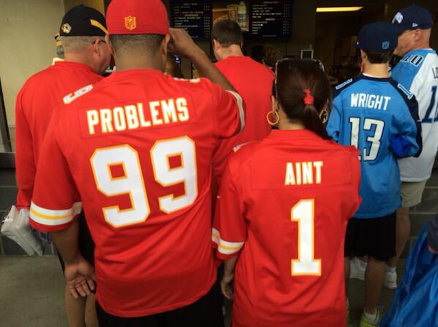 A couple wearing 'Problems 99' and 'Ain't 1' jerseys.