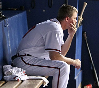 Chipper Jones sits dejected in the dugout as Atlanta's lead in the NL East dwindles.  (AP)