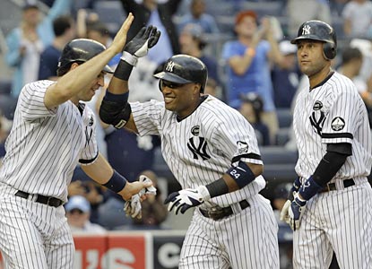 Mark Teixeira and Derek Jeter greet Robinson Cano after he drives them in with a fifth-inning grand slam.  (AP)