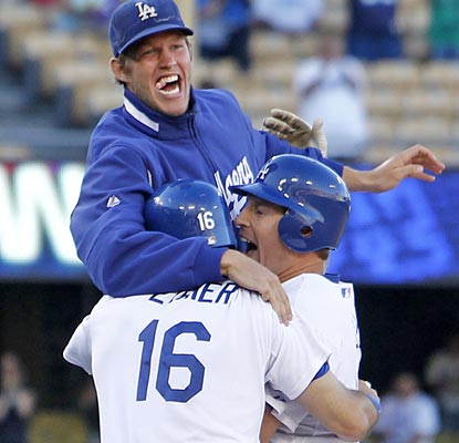 Clayton Kershaw (top) and Andre Ethier (left) mob A.J. Ellis after he delivers the game-winning single in the 11th.  (AP)
