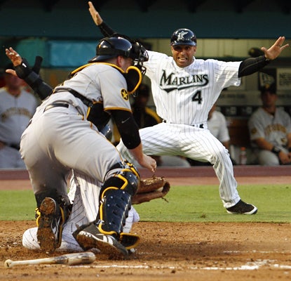 Marlins third base coach Joey Espanda celebrates as Emilio Bonifacio slides in for a run in the second inning. (AP)