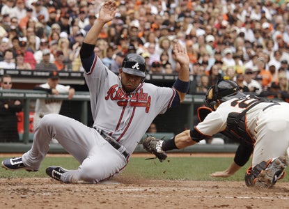 Alex Gonzalez slides safely across home plate on a fielder's choice in the seventh inning of the Braves' win over the Giants. (AP)