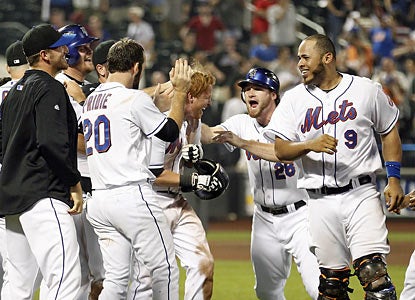 Justin Turner (holding helmet) is mobbed at home after he leads the Mets to a win after getting hit with two outs in the 13th. (AP)