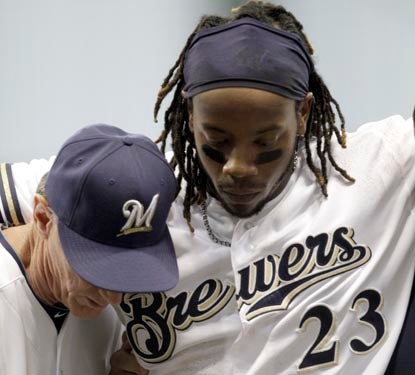 Rickie Weeks is helped off the field by Brewers manager Ron Roenicke after injuring his ankle running to first base. (AP)