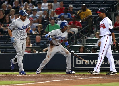 Dee Gordon (center) scores the go-ahead run in the top of the 10th on a sacrifice fly hit by Juan Rivera. (Getty Images)