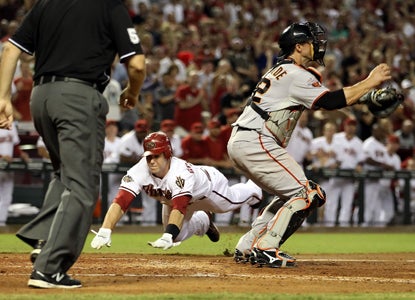 Paul Goldschmidt -- who lines a critical two-run triple in the eighth -- dives past catcher Eli Whiteside to score.  (Getty Images)
