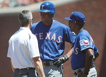 Alexi Ogando gets checked out by a trainer and Rangers manager Ron Washington after injuring himself in the fourth inning.  (Getty Images)