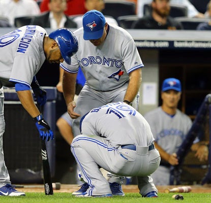 Teammates check on slugger Jose Bautista, who injures his left wrist on a swing in the eighth inning. (Getty Images)