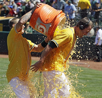The A's Brandon Hicks (right) receives the hero treatment after he wins the game with a walk-off home run. (AP)