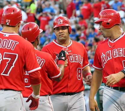 Teammates congratulate Kendrys Morales (center), who hits homers from both sides of the plate in the same inning. (Getty Images)