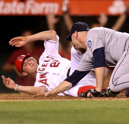 Peter Bourjos slides past Mariners pitcher Josh Kinney in the bottom of the ninth to provide the Angels with the winning run.  (Getty Images)