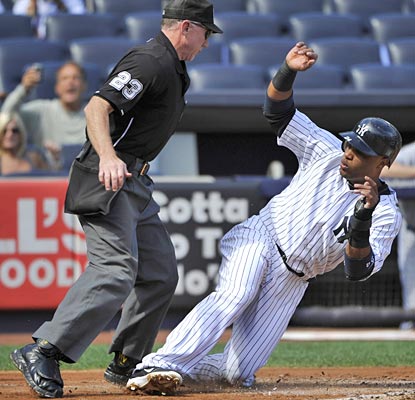 Robinson Cano has to avoid home-plate umpire Lance Barksdale while scoring on a sacrifice fly in the first inning.  (AP)