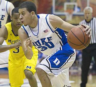 Michigan's Trey Burke tries to close in on a driving Seth Curry during the first half. Curry winds up with 17 points.  (AP)
