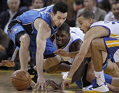 Orlando's J.J. Redick battles for a loose ball with Golden State's Festus Ezeli and Stephen Curry. (AP)