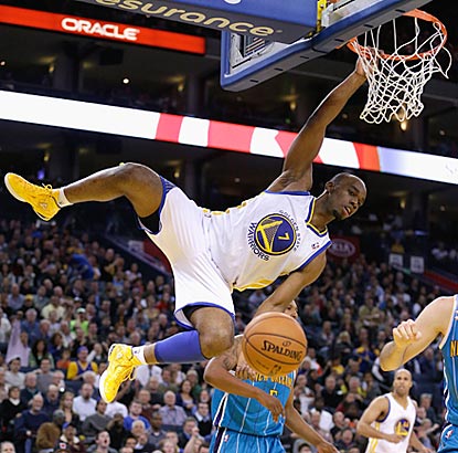 Carl Landry hangs on after dunking during the fourth quarter, and the Warriors hang on to beat the Hornets.  (Getty Images)