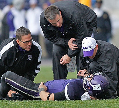 Northwestern coach Pat Fitzgerald checks on Dan Persa, who suffers a season-ending injury after throwing the go-ahead TD.  (US Presswire)