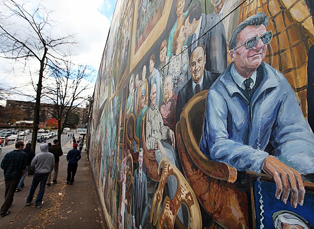 PSU students walk past a mural entitled 'Inspiration,' which depicts ex-coach Joe Paterno. (Getty Images)