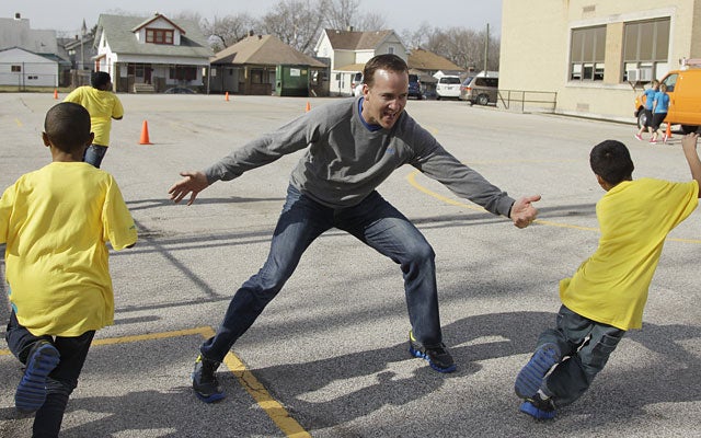 Peyton Manning at play with some Indy kids, who should be familiar with his recent childish behavior. (AP)