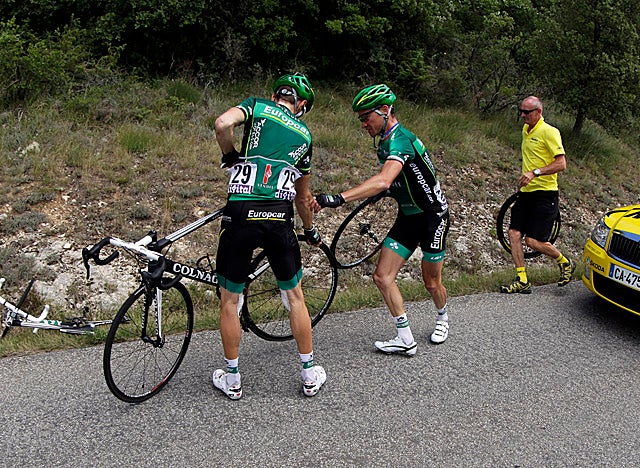 Riders help with a tire change after hitting a stretch of tacks on the road. (Getty Images)