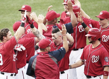 With the bases loaded in the bottom of the 10th, Brad Lidge nicks Jonny Gomes (center) with a pitch giving Washington the win. (AP)