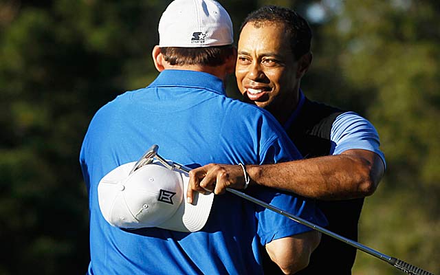 Tiger Woods gets a hug from partner Tony Romo, who thinks Woods has a 'great shot this week.' (Getty Images)