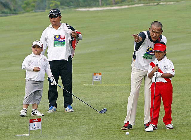 Two competitors get help from their dads at the Kids Golf World Championship in Malaysia. (AP)