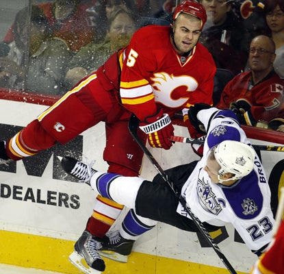 The Kings' Dustin Brown (right) takes a hard hit from the Flames' Mark Giordano during the second period. (AP)
