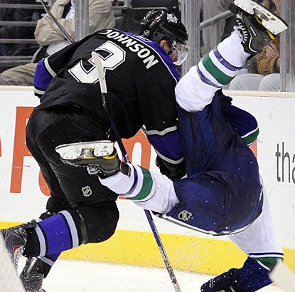 Kings defenseman Jack Johnson upends Canucks left winger Mason Raymond with a big check. (AP)