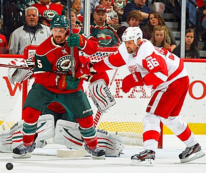 The Red Wings' Tomas Holmstrom battles for the puck with Greg Zanon of the Wild. (Getty Images)
