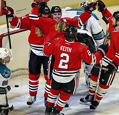 Chicago's Patrick Sharp is swarmed by teammates after he scores the win goal in overtime against the Sharks. (AP)