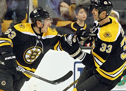Brad Marchand enjoys his first career three-goal game and career-high five points with team captain Zdeno Chara. (AP)