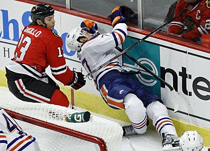 Daniel Carcillo costs the Blackhawks when he gets a game misconduct for this boarding hit on Tom Gilbert in the second period. (AP)
