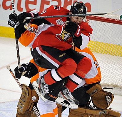 Ottawa's Nick Foligno scores a goal and, here, takes a puck off the thigh trying to shield Philly goalie Ilya Bryzgalov. (Getty Images)
