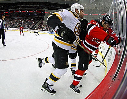 Boston's Milan Lucic (left) slams New Jersey's Mark Fayne into the boards at the Prudential Center in the Bruins' 4-1 win. (US Presswire)