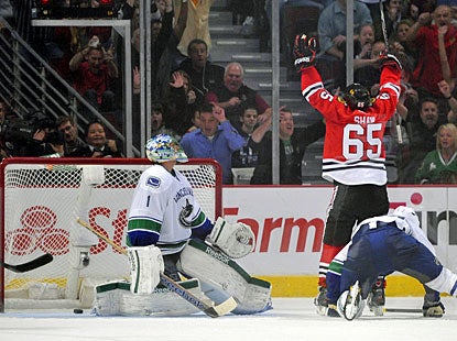 Andrew Shaw deflects the puck past Roberto Luongo and celebrates the victory against Vancouver. (US Presswire)