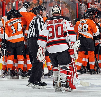 The Flyers celebrate their Game 1 overtime victory as Devils goalie Martin Brodeur has words with a linesman.  (Getty Images)