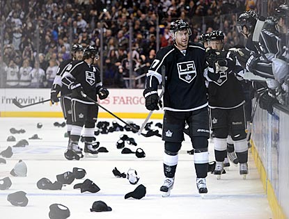 Jeff Carter (front) accepts congratulations from his teammates on his hat trick while giveaway hats rain down upon the ice.  (Getty Images)