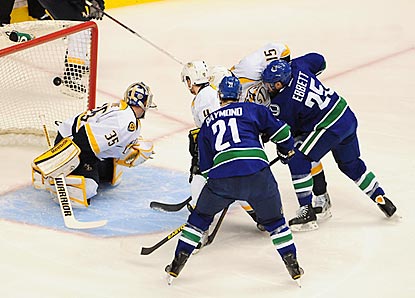 Despite a crowd in front, Andrew Ebbett (right) shoots the puck past Nashville's Pekka Rinne to open the scoring.  (USATSI)