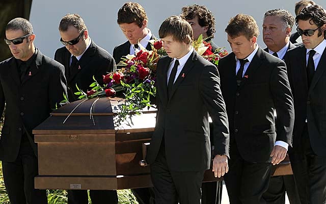 Drivers Tony Kanaan (left) and Dario Franchitti (right) help carry the coffin of Dan Wheldon on Saturday. (AP)