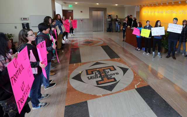 Protestors stand outside Dave Hart's press conference. (USATSI)