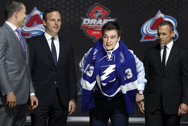 Jonathan Drouin slips on his new sweater surrounded by the Lightning management. (USATSI)